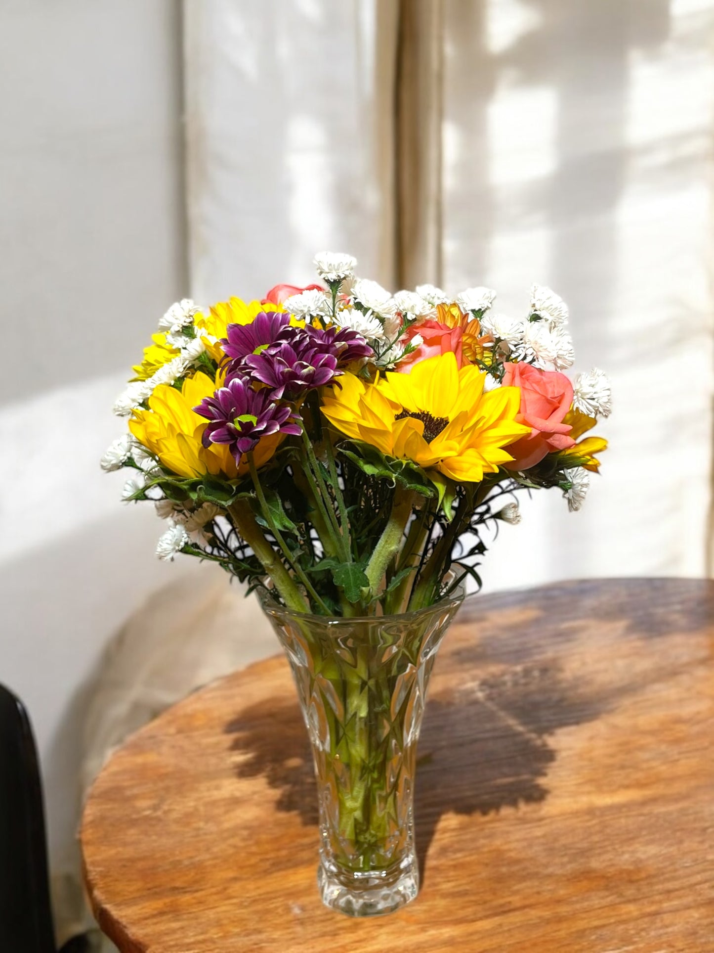 Tropical arrangement with sunflowers in a glass vase.