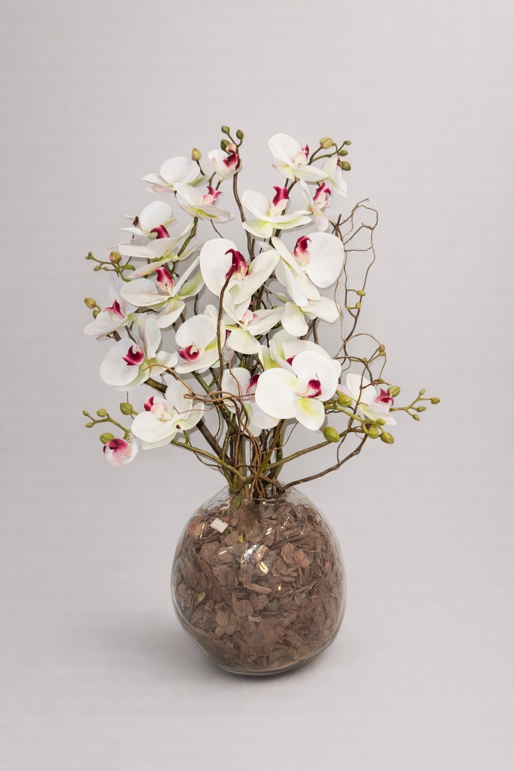 Artificial arrangement of white orchids in a glass vase.