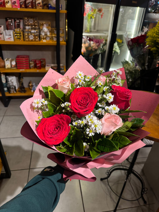 A delicate bouquet with red roses and pink roses.