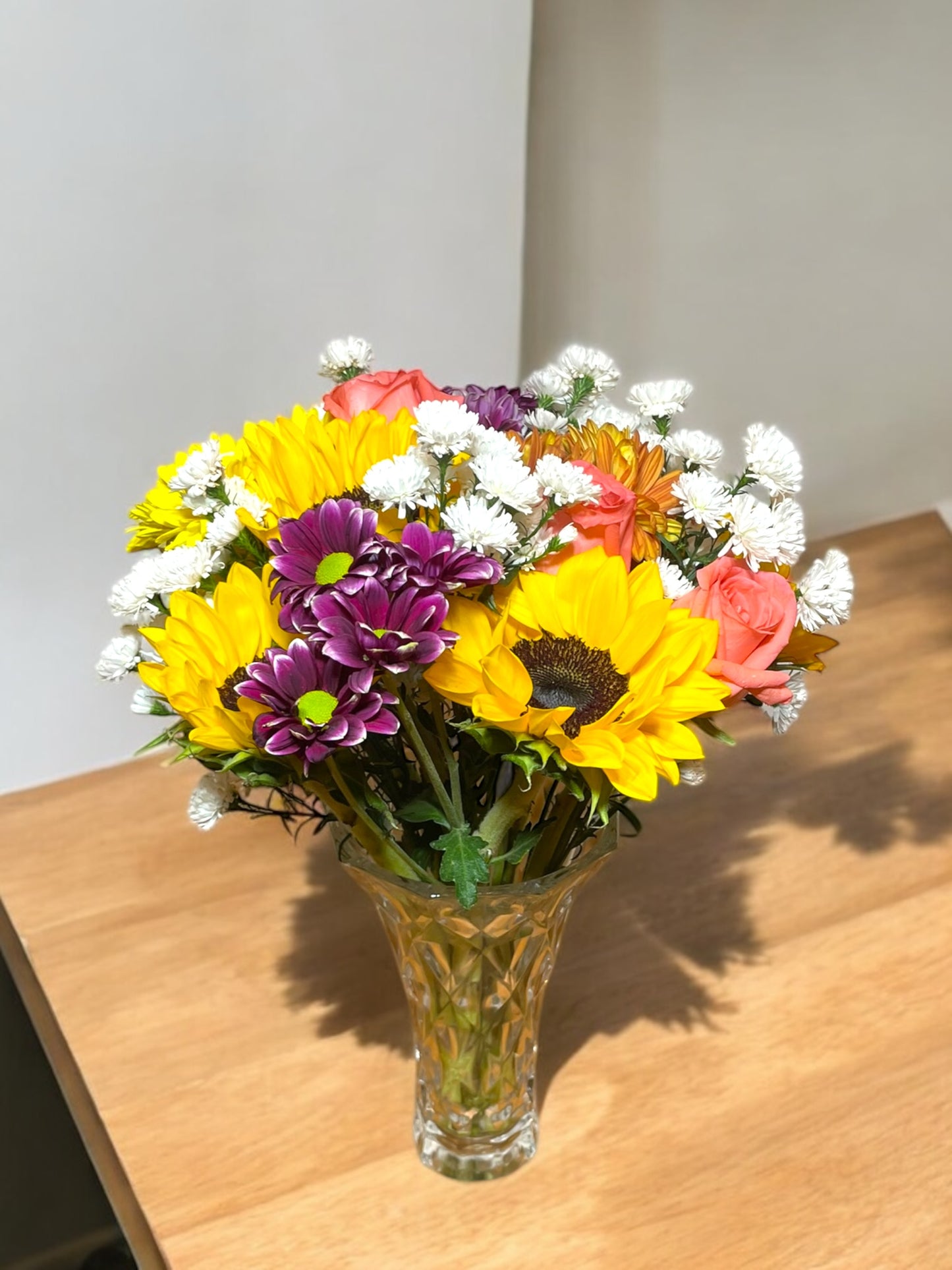 Tropical arrangement with sunflowers in a glass vase.