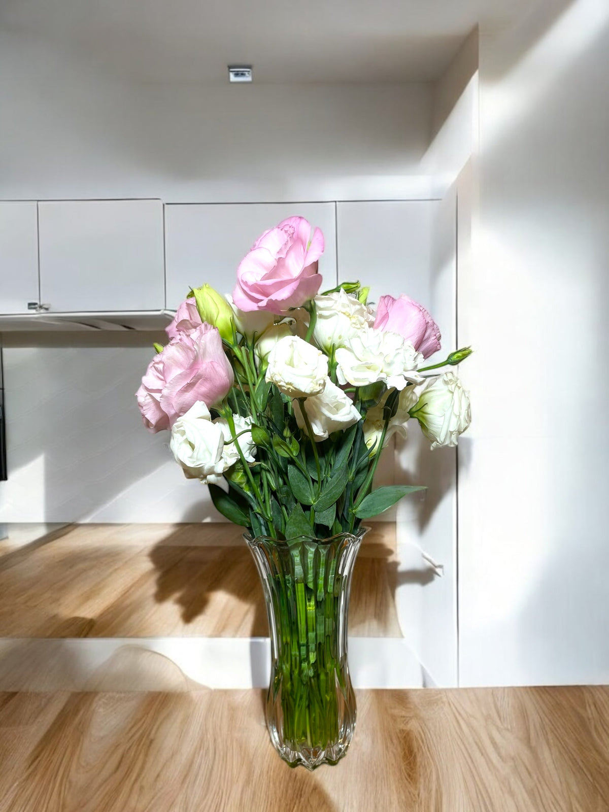 Exemplo de arranjo do plano Signature: lisianthus rosa e branco em vaso de vidro. As flores variam conforme a estação.