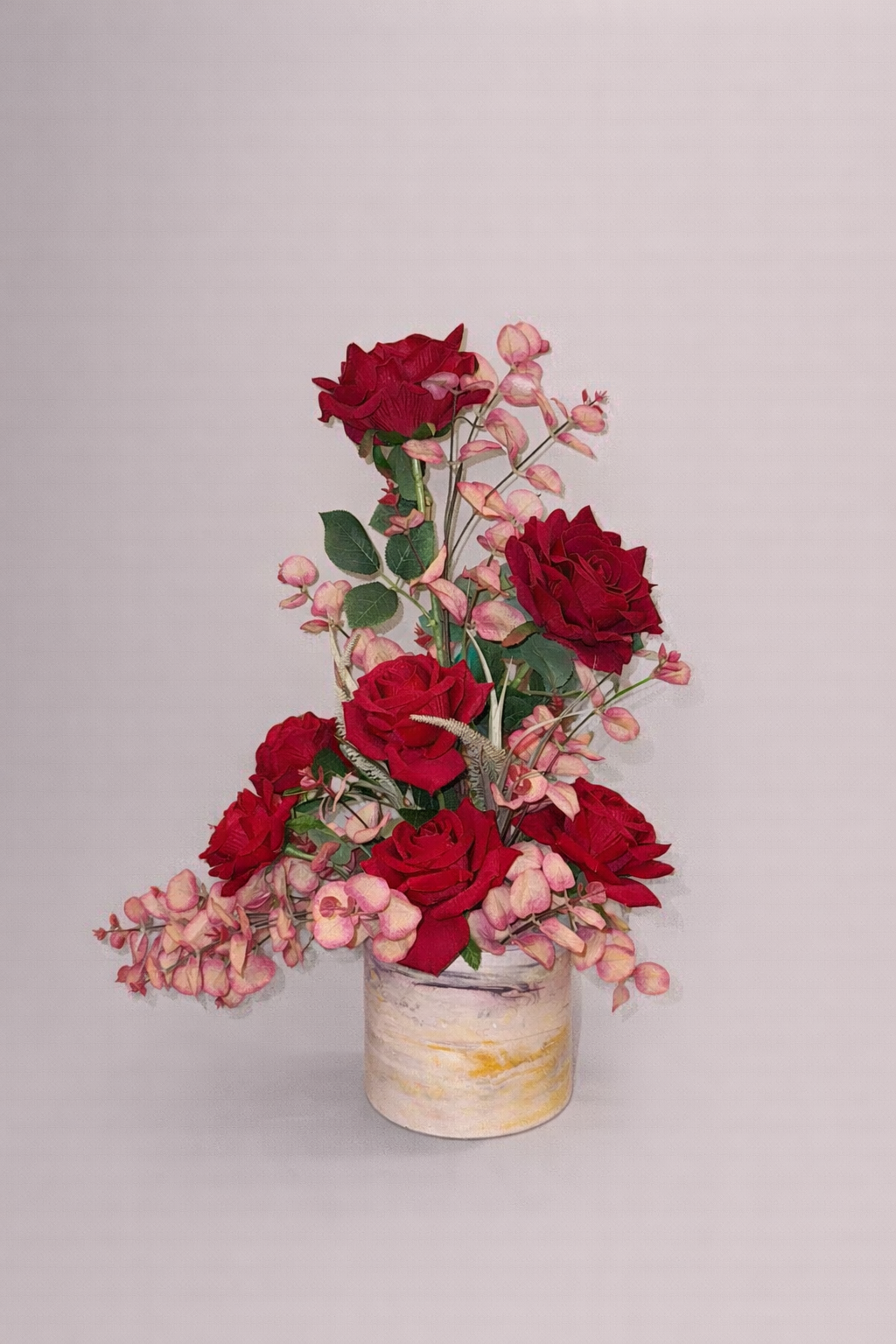 Artificial arrangement of red roses with delicate flowers.